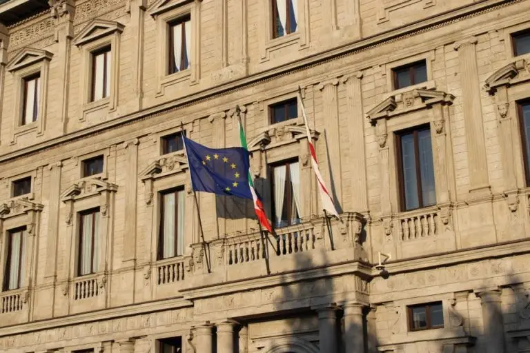 A beautiful example of European architecture featuring flags, located in a historic area of Milan, Italy.